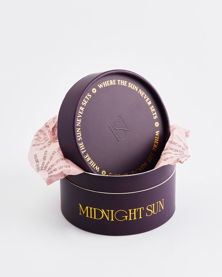 Round purple packaging with 'Midnight Sun' text on a light gray background