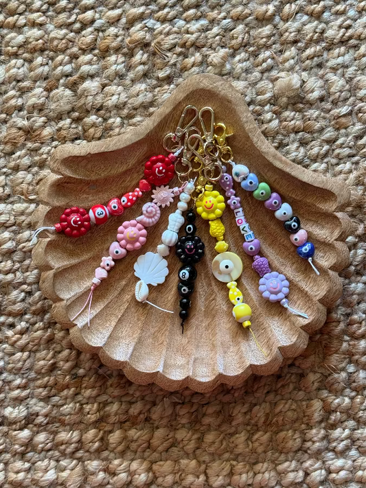 Colorful beaded keychains on a shell-shaped stand on a textured surface