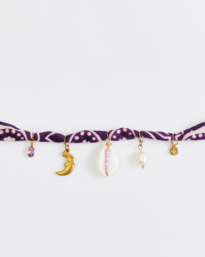 Purple bracelet with various charms on a white background