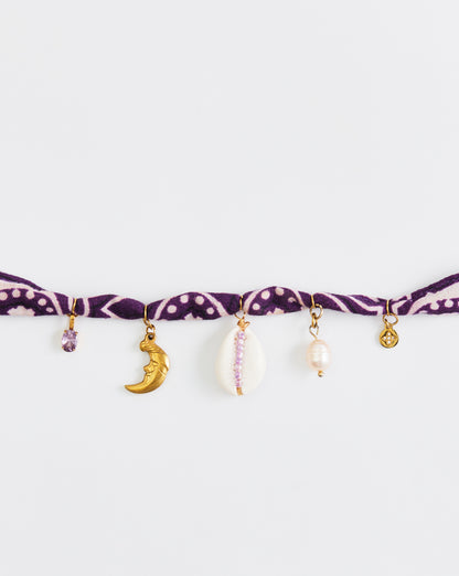 Purple bracelet with various charms on a white background