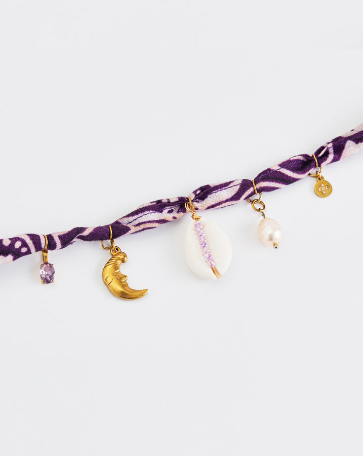 Bracelet with purple pattern and various charms on a white background