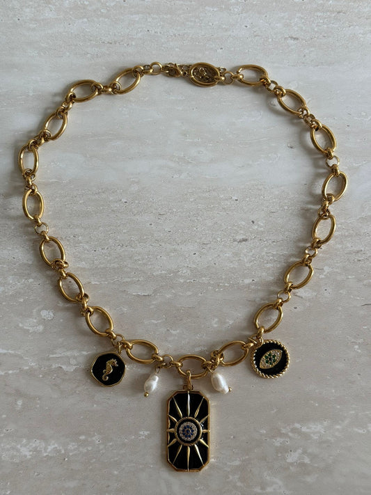 A gold stainless steel chain necklace with gold stainless steel charms and freshwater pearls, featuring adjustable length and a sun motif charm.