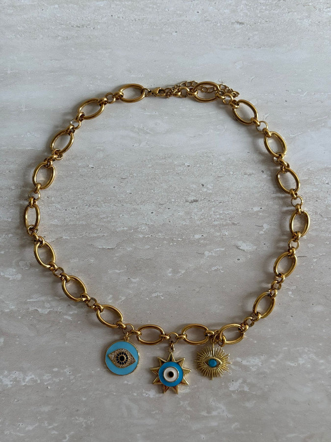 Gold chain bracelet with eye-shaped charms on a light gray background