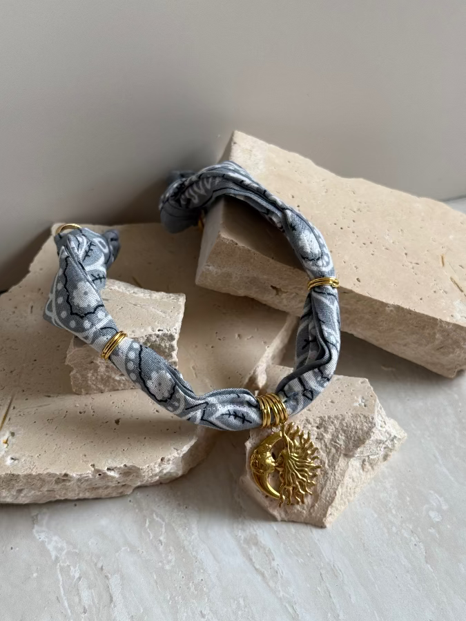 A bracelet with a paisley bandana pattern and a gold stainless steel charm, displayed on a neutral background.