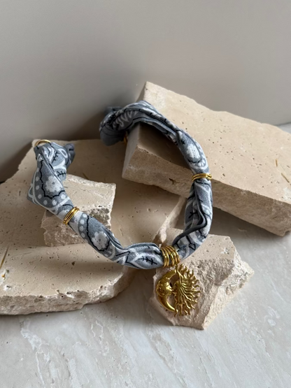 A bracelet with a paisley bandana pattern and a gold stainless steel charm, displayed on a neutral background.