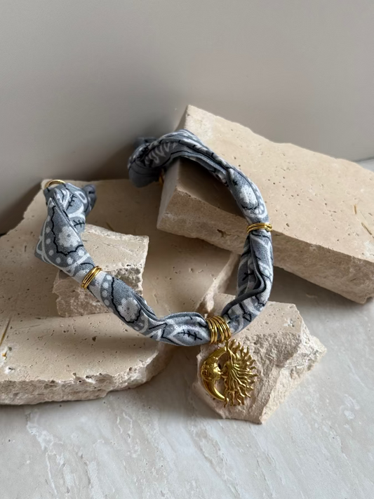 A bracelet with a paisley bandana pattern and a gold stainless steel charm, displayed on a neutral background.