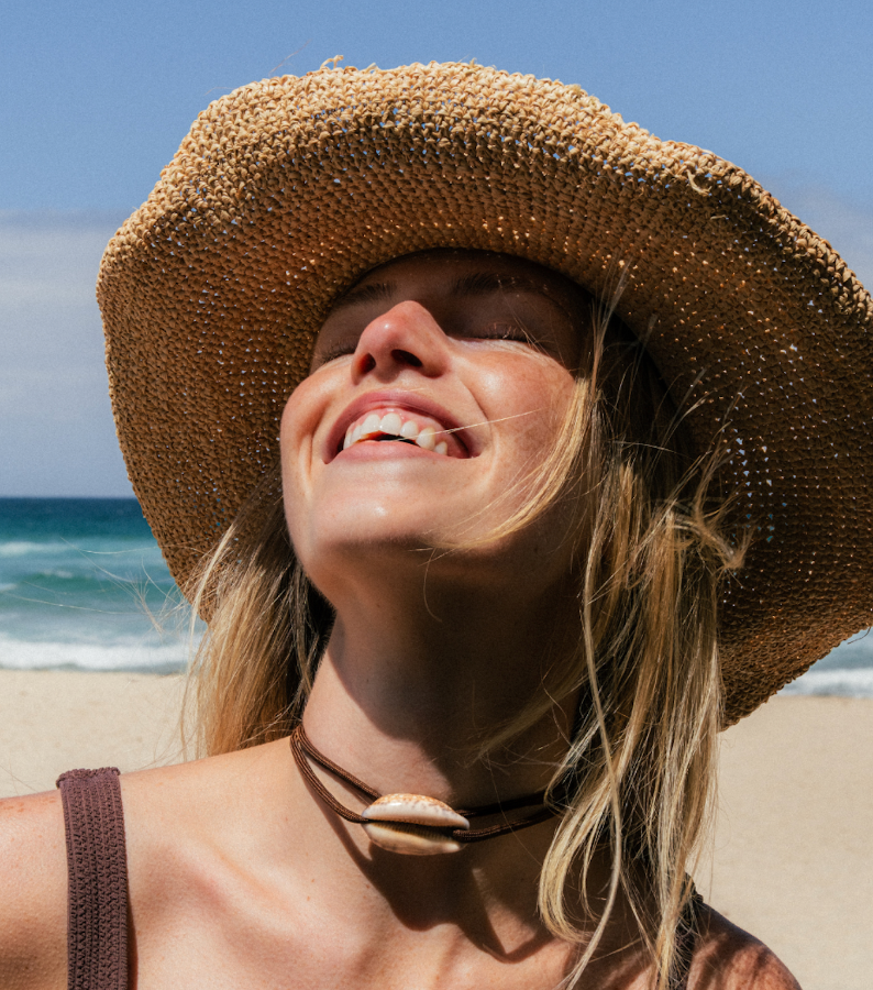 Woman wearing a straw hat on a beach with ocean view