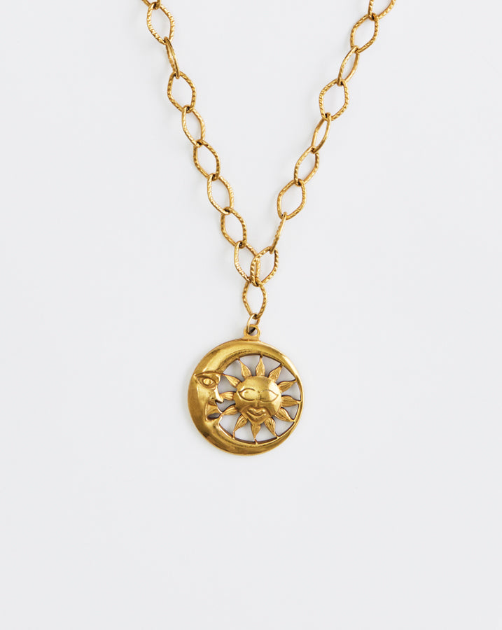Gold necklace with a sun and moon pendant on a white background