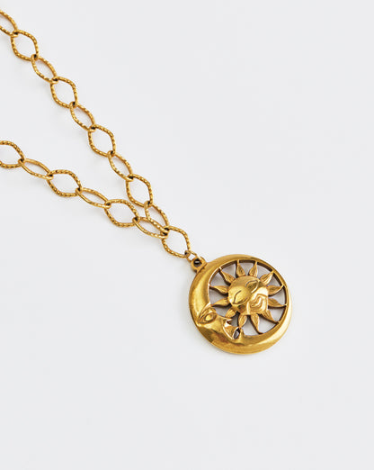 Gold necklace with a sun and moon pendant on a white background
